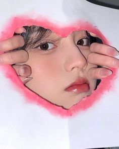 a woman holding her hands up to the face of a heart shaped piece of paper