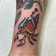 a colorful crab tattoo on the wrist and arm with flowers in it's center