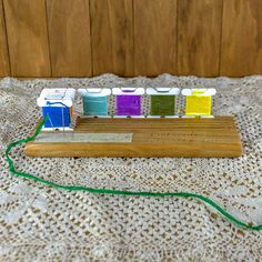 a row of colorful toothbrushes sitting on top of a wooden board with green cord