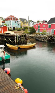 two boats are docked in the water next to some colorful houses and docking posts