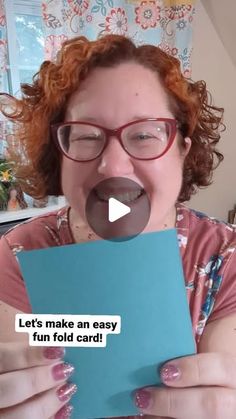 a woman with red hair and glasses holding a piece of paper in front of her face