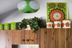 a kitchen with green and white decor on the counter top, potted plants in front of an overhead light