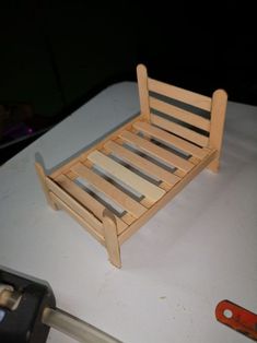 a wooden bed frame sitting on top of a table next to a wrench and screwdriver