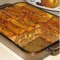 a pan filled with food sitting on top of a counter next to a bowl of fruit