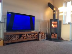 a flat screen tv sitting on top of a wooden stand next to a fire place