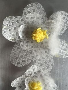 three pieces of paper with yellow flowers in them on a metal surface, one is cut out and the other has been made from plastic