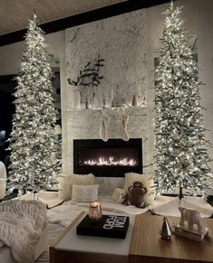 a living room decorated for christmas with white trees and lights on the fireplace mantles