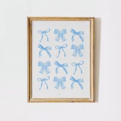 a painting with blue bows hanging on the wall next to a wooden frame that has been framed