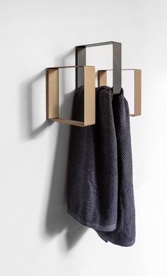 two towels are hanging on the wall next to a towel rack with three square mirrors