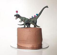 there is a cake with two dinosaurs on top