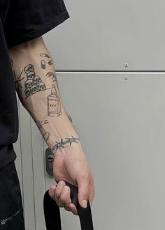 a man with tattoos on his arm holding onto a black handle to a metal door