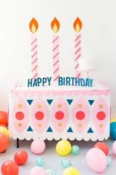 a birthday cake sitting on top of a table surrounded by balloons