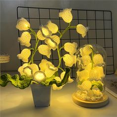 a vase filled with flowers sitting on top of a table next to a light bulb