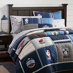 a bed with a basketball themed comforter and pillows on top of it, in a bedroom