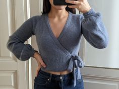 a woman taking a selfie in front of a mirror wearing a sweater and jeans