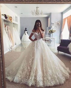 a woman standing in front of a mirror wearing a wedding dress