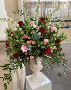 a vase filled with lots of flowers sitting on top of a white pedestal