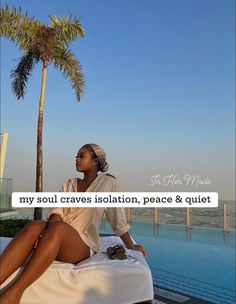 a woman sitting on top of a bed next to a palm tree in front of a swimming pool