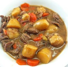 a white bowl filled with beef and potatoes