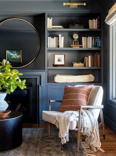 a living room with bookshelves and a chair in front of a fire place