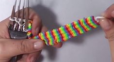 two hands holding forks with multicolored strings attached to the ends of each fork