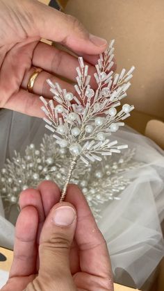 a person holding a small white flower in their left hand and wearing a wedding ring