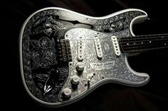 an intricately designed guitar is displayed on a black background with white flowers and leaves