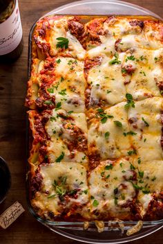 a casserole dish with meat, cheese and sauce in it on a wooden table