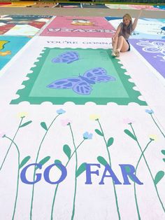 a woman is sitting on the ground in front of some painted flowers and butterfly designs