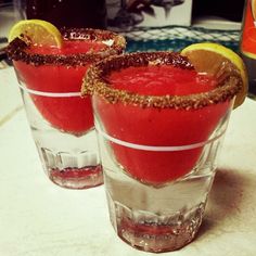 two glasses filled with watermelon and topped with lemon wedges on a table