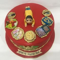 there is a red cake with gold trimmings and decorations on it, including a doll