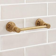 a gold towel bar on a white brick wall