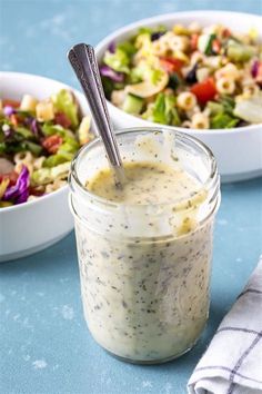 two bowls with salad and dressing in them on a blue tablecloth next to each other