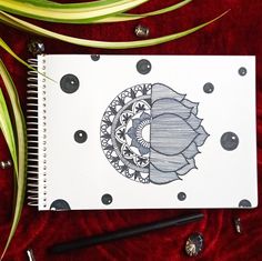 a spiral notebook with an image of a flower on the cover and some pens next to it