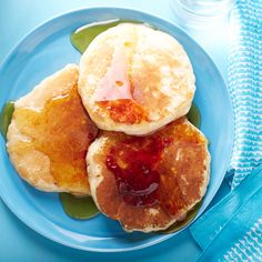 three pancakes on a blue plate with syrup