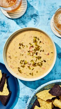 two bowls of dip and tortilla chips on a blue tablecloth with beer in the background