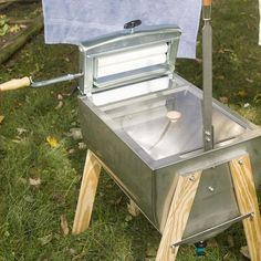 an outdoor bbq grill sitting on top of a grass covered field next to a blue towel