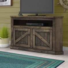 a flat screen tv sitting on top of a wooden entertainment center next to a rug