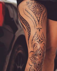 a close up of a person's leg with tattoos on it and a car in the background