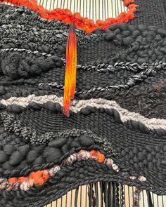 an orange and black piece of art that looks like woven material