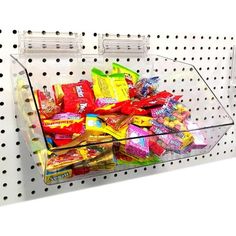 a plastic container filled with candy on top of a white shelf next to polka dots