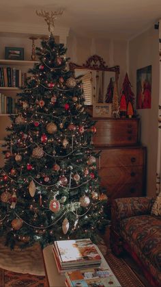 a living room with a christmas tree in the corner and books on the coffee table