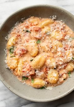 a bowl filled with pasta and sauce on top of a marble countertop next to a spoon