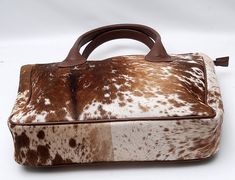 a brown and white spotted purse on a white surface with a wooden handle in the shape of a handbag