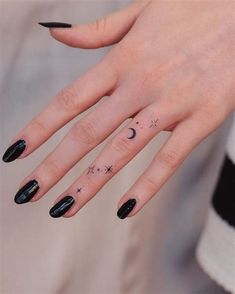 a woman's hand with black nail polish and stars on her fingers, while she has