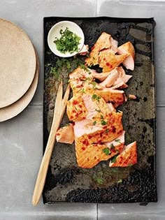 some food is laying out on a tray with chopsticks and a small bowl