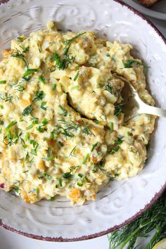 a white bowl filled with mashed potatoes and garnished with fresh herbs