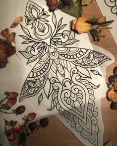 an artistically designed piece of paper with leaves and flowers around it on a table