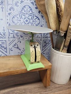 an old fashioned kitchen scale sitting on top of a wooden bench next to utensils