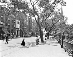 an old black and white photo of people walking down the street